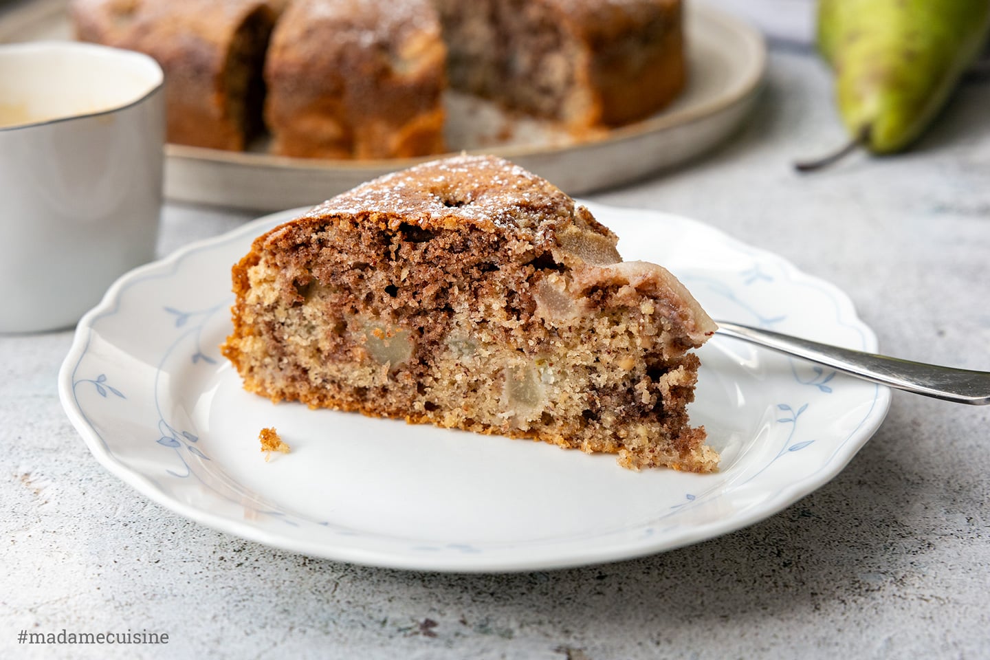 Birnen-Nuss-Kuchen mit Marmoreffekt, Kuchenstück mit Gabel auf blau gemustertem Teller