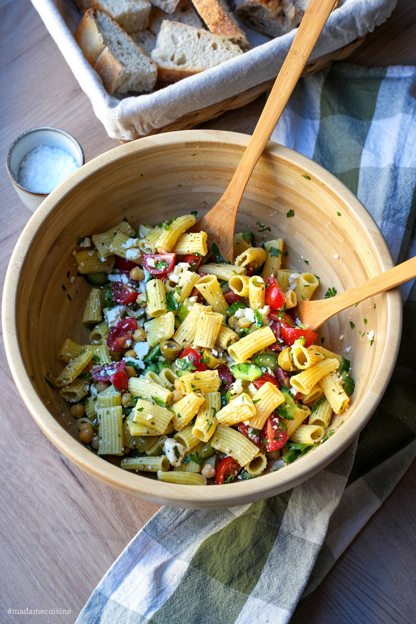 Mediterraner Nudelsalat mit Feta, Kichererbsen und Kirschtomaten in großer Holzschüssel von oben