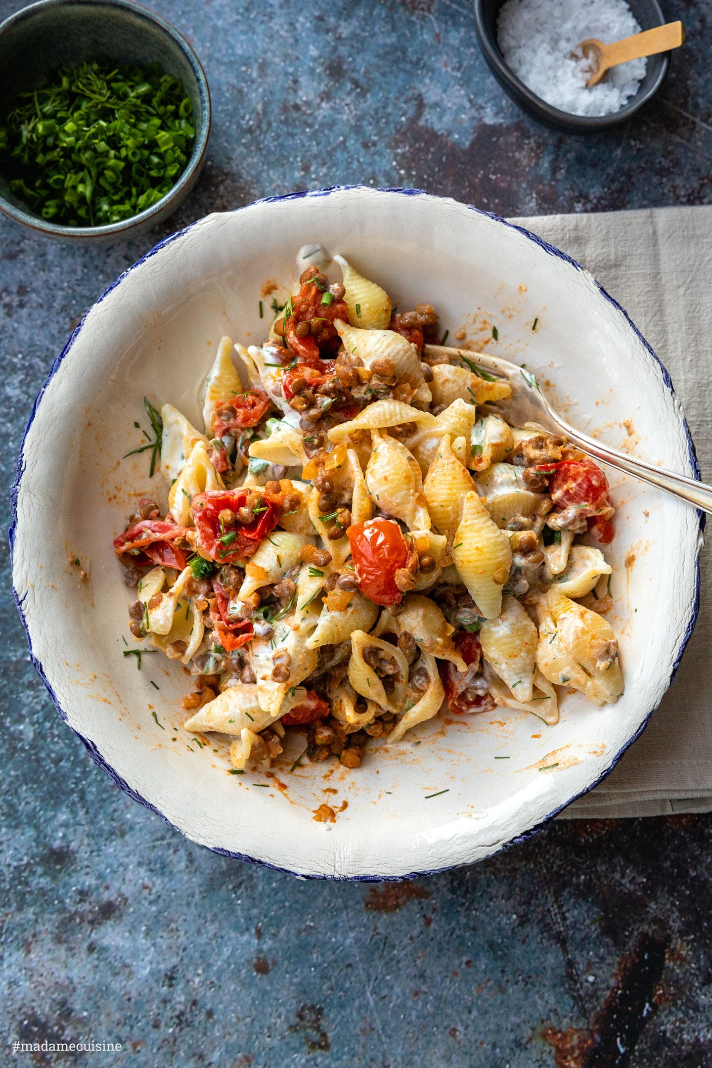 Pasta mit Linsen und Tomaten von oben, daneben Schälchen mit Kräutern und Meersalz