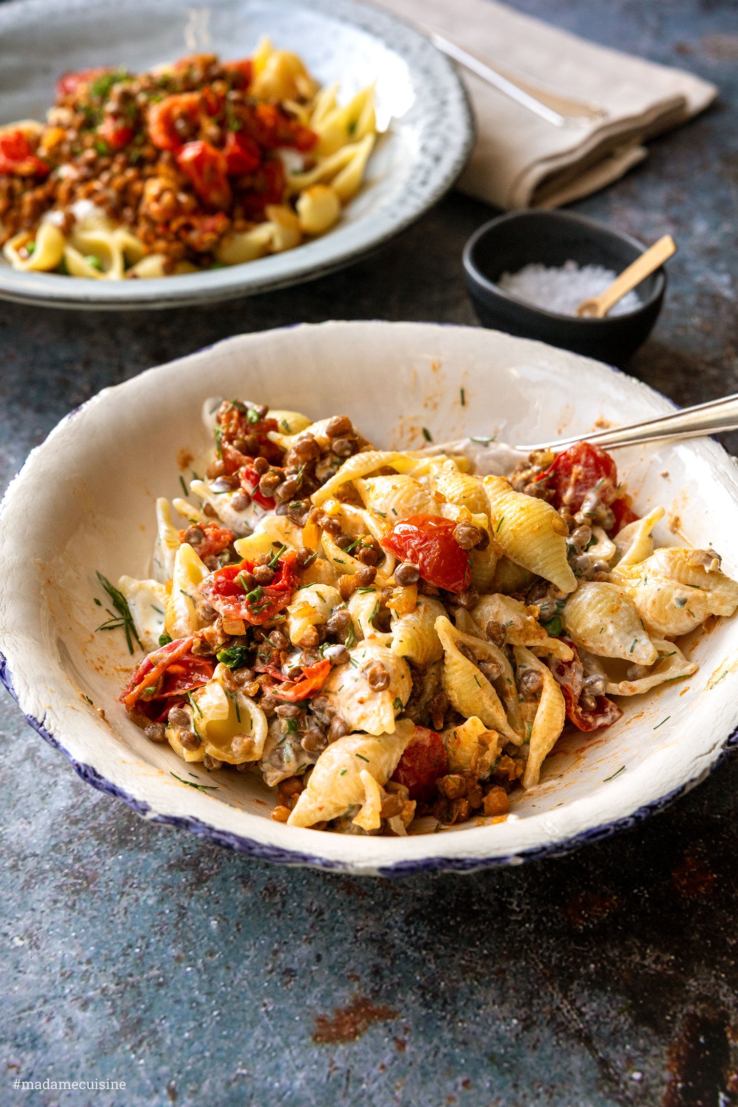 Fertig vermischte Pasta mit Kirschtomaten und Joghurt in einer weißen Schüssel
