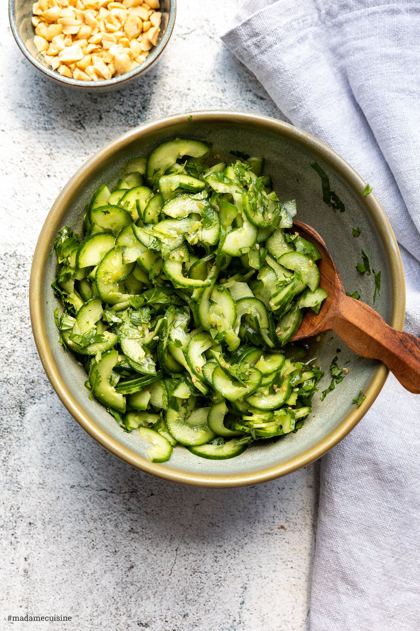 Gurkensalat mit Koriander und Sesam, daneben Erdnüsse und eine Leinenserviette