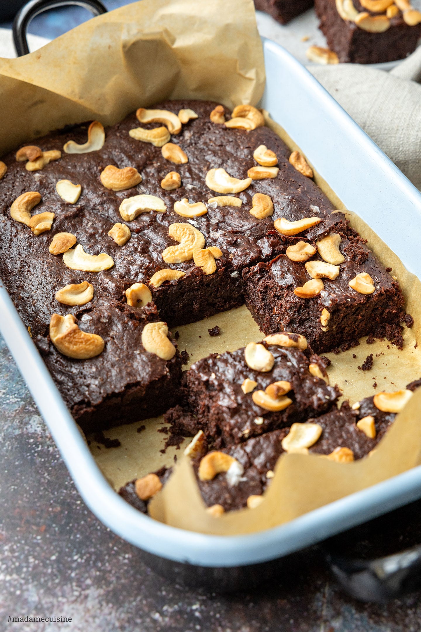 Saftige vegane Cashew-Brownies in der Backform, einige Stücke bereits angeschnitten