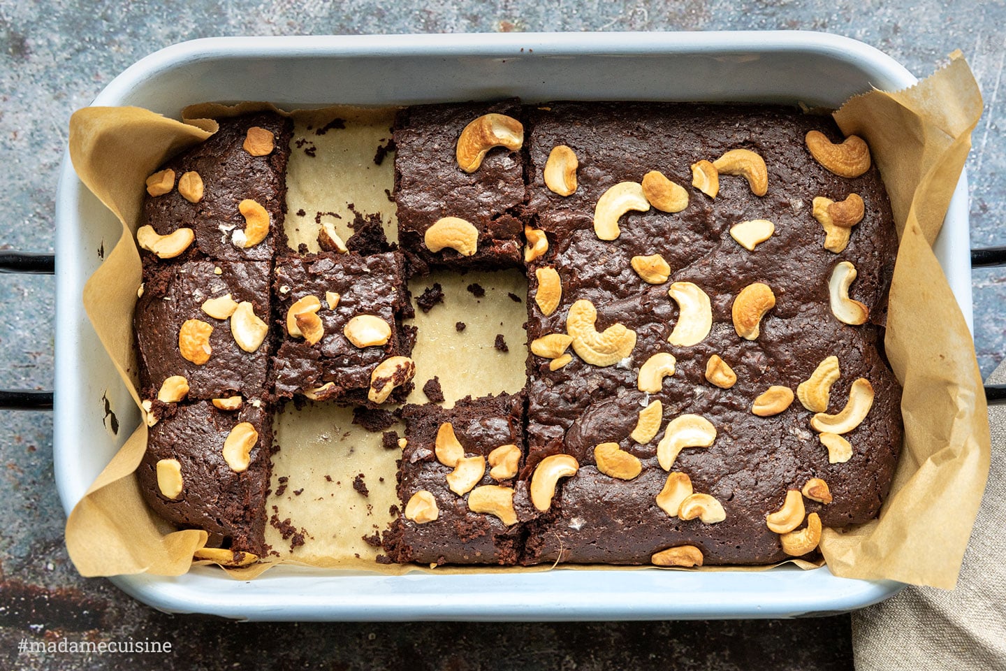 Vegane Brownies mit Cashewnüssen in einer hellblauen Backform, von oben fotografiert, mit grobem Meersalz bestreut