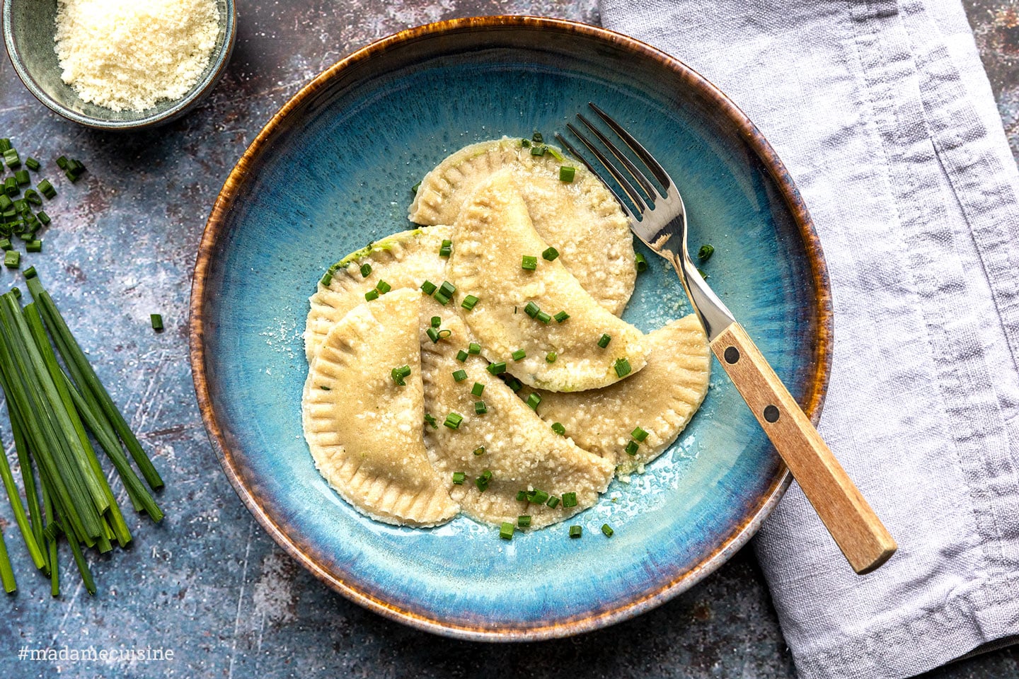 Südtiroler Schlutzkrapfen mit Parmesan und Schnittlauch auf blauem Teller
