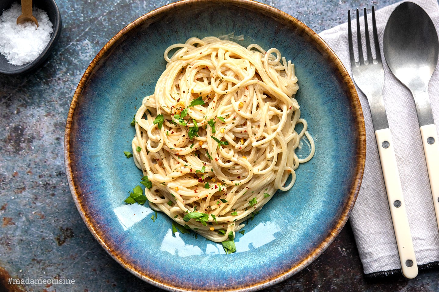 Spaghetti mit Tahini-Sauce in einer blauen Schale, garniert mit Petersilie und Chiliflocken