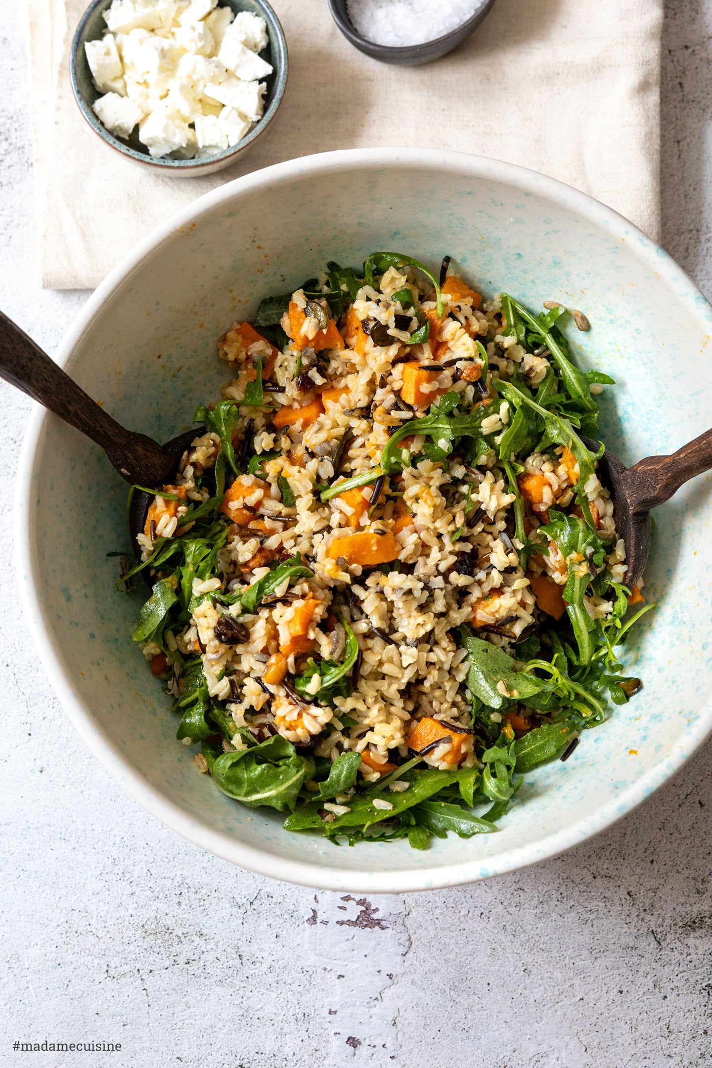 Frisch zubereiteter Salat in einer hellblauen Schüssel mit zwei Holzlöffeln