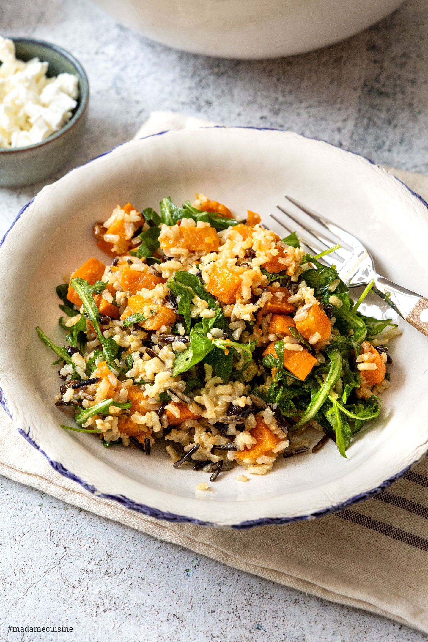 Wildreis-Süßkartoffel-Salat mit Rucola und Feta auf einem Teller mit Gabel