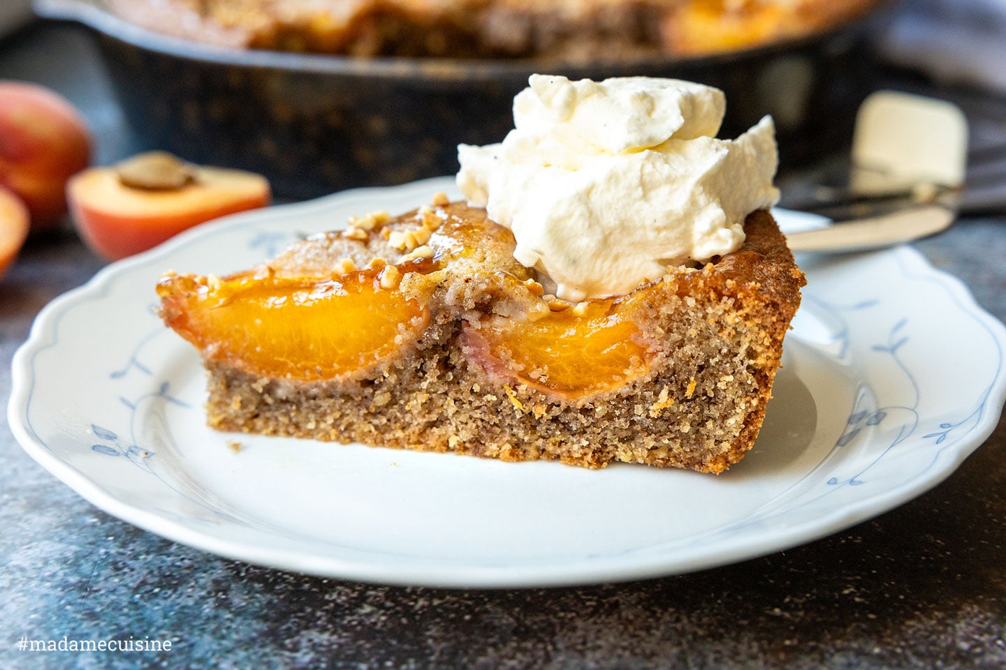 Aprikosenkuchen mit Walnüssen, angeschnitten auf Teller mit Schlagsahne
