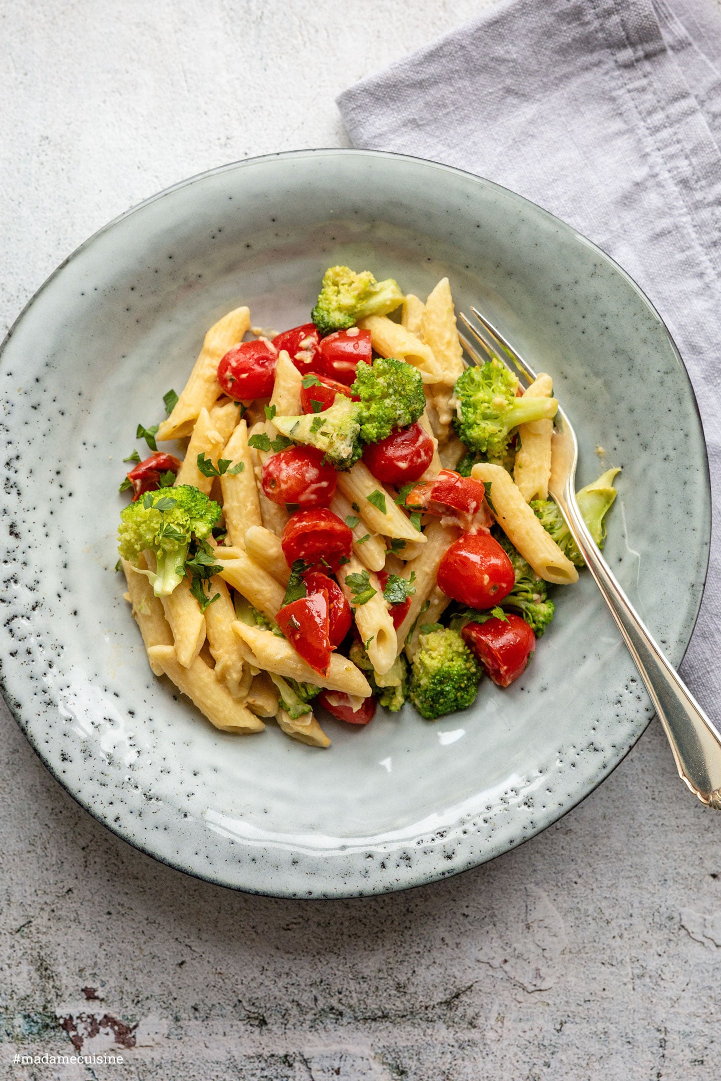 Hummus-Pasta mit Brokkoli und Tomaten, mit Petersilie bestreut