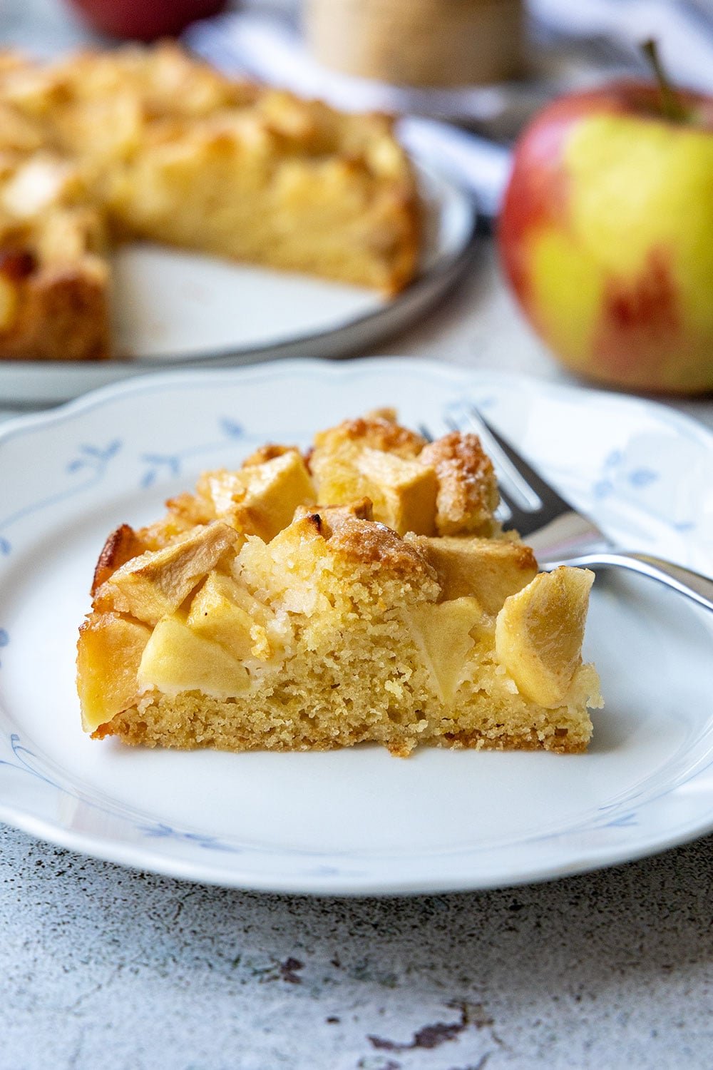 Ein Stück kleiner Apfelkuchen auf blau-weißem Teller mit Gabel