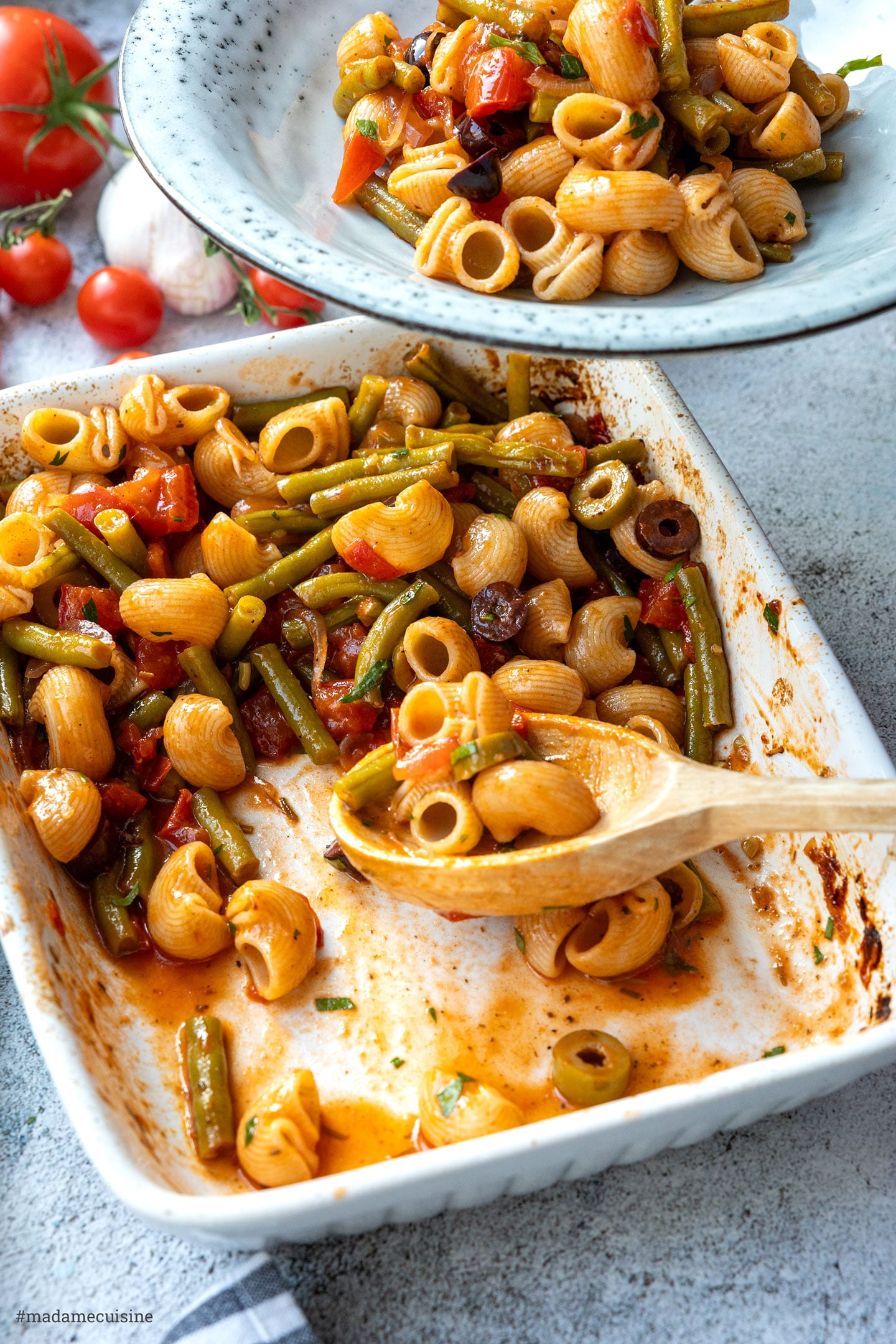 Pasta mit grünen Bohnen und Tomaten wird auf Teller verteilt