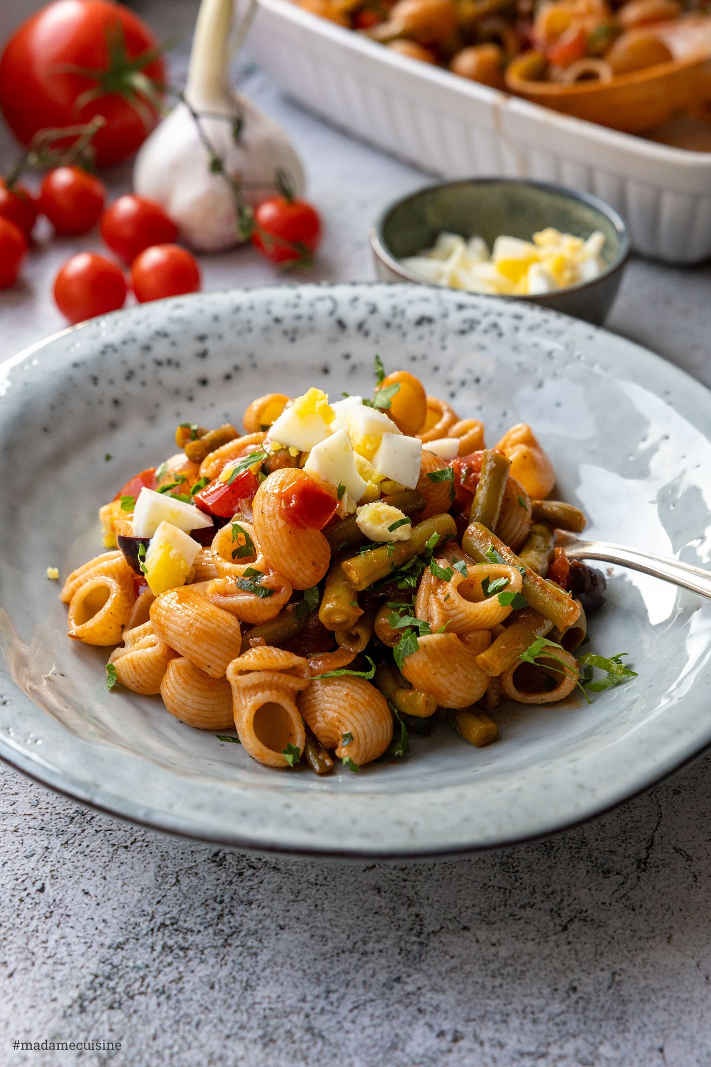 Pasta auf Teller verteilen und mit grob gehackten Ei und Petersilie garnieren