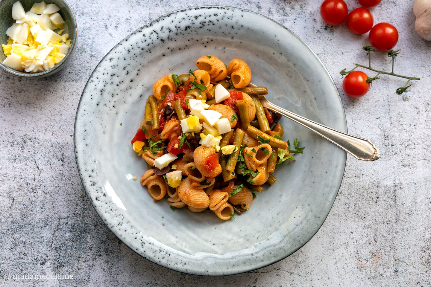 Pasta mit grünen Bohnen und Tomaten in einer Schüssel, bestreut mit gehacktem Ei und Petersilie