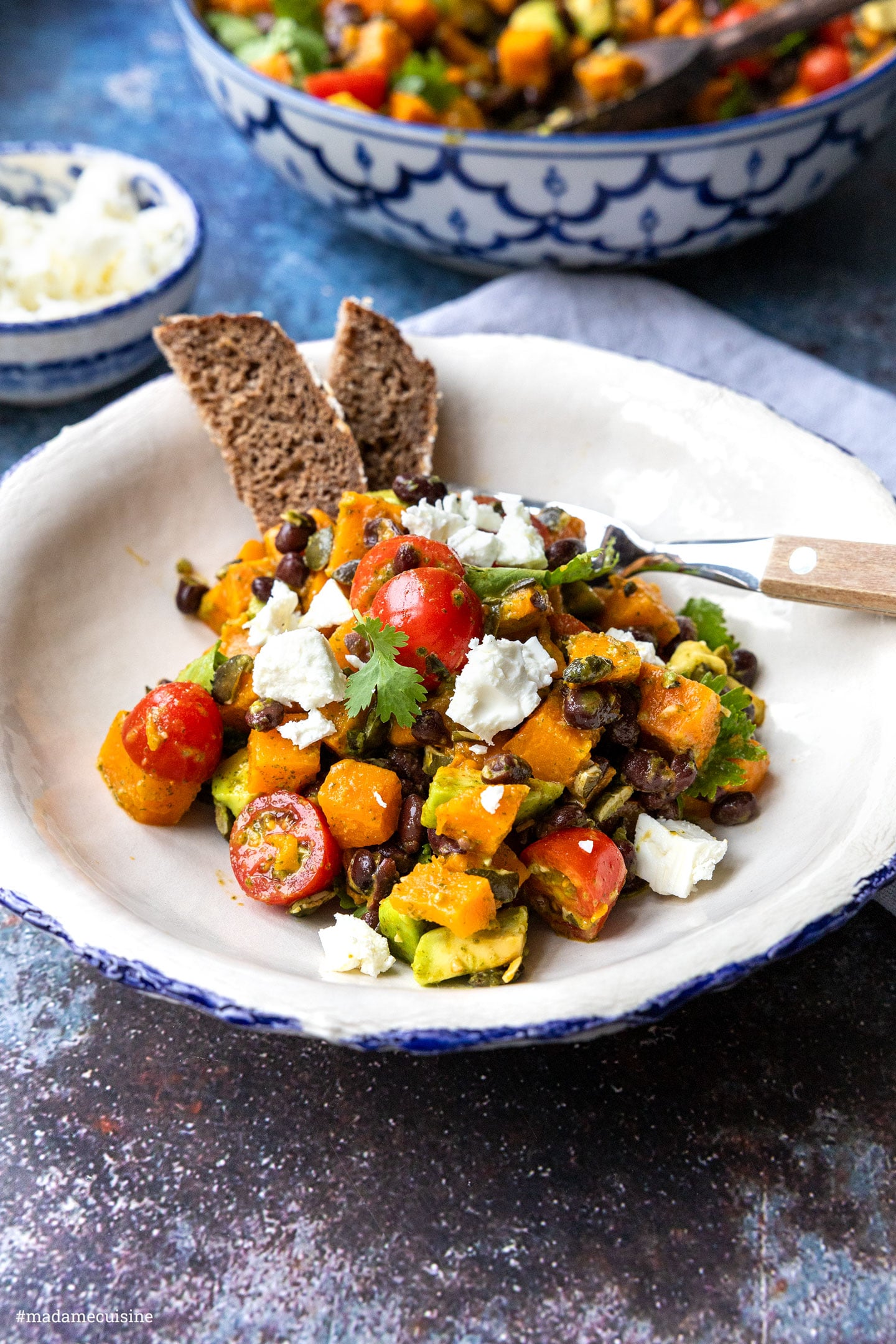 Süßkartoffel-Salat mit Feta und Brot auf weißem Teller