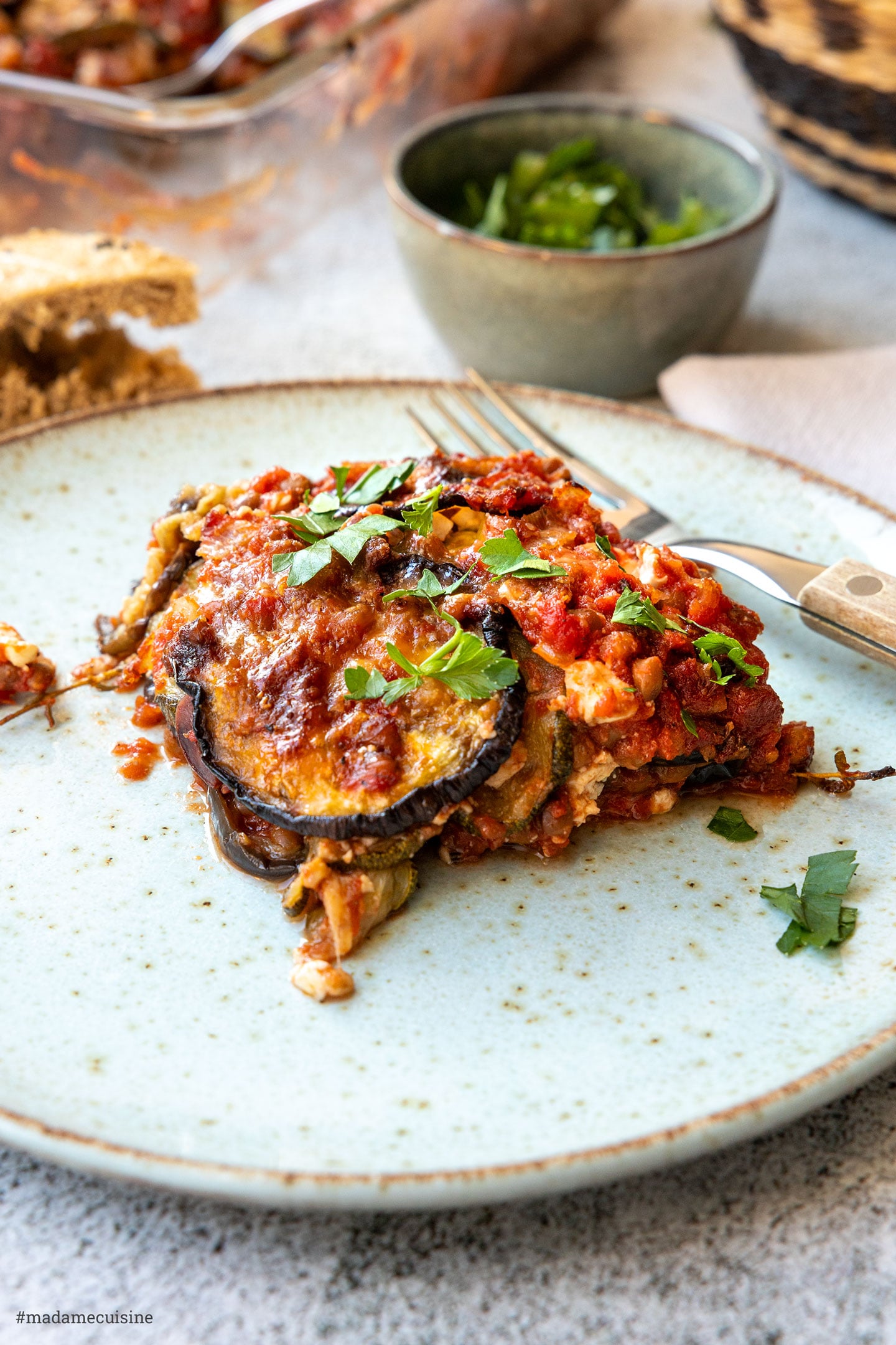 Portion Moussaka ohne Fleisch mit Auberginen-Zucchini-Schichten auf rustikalem Teller