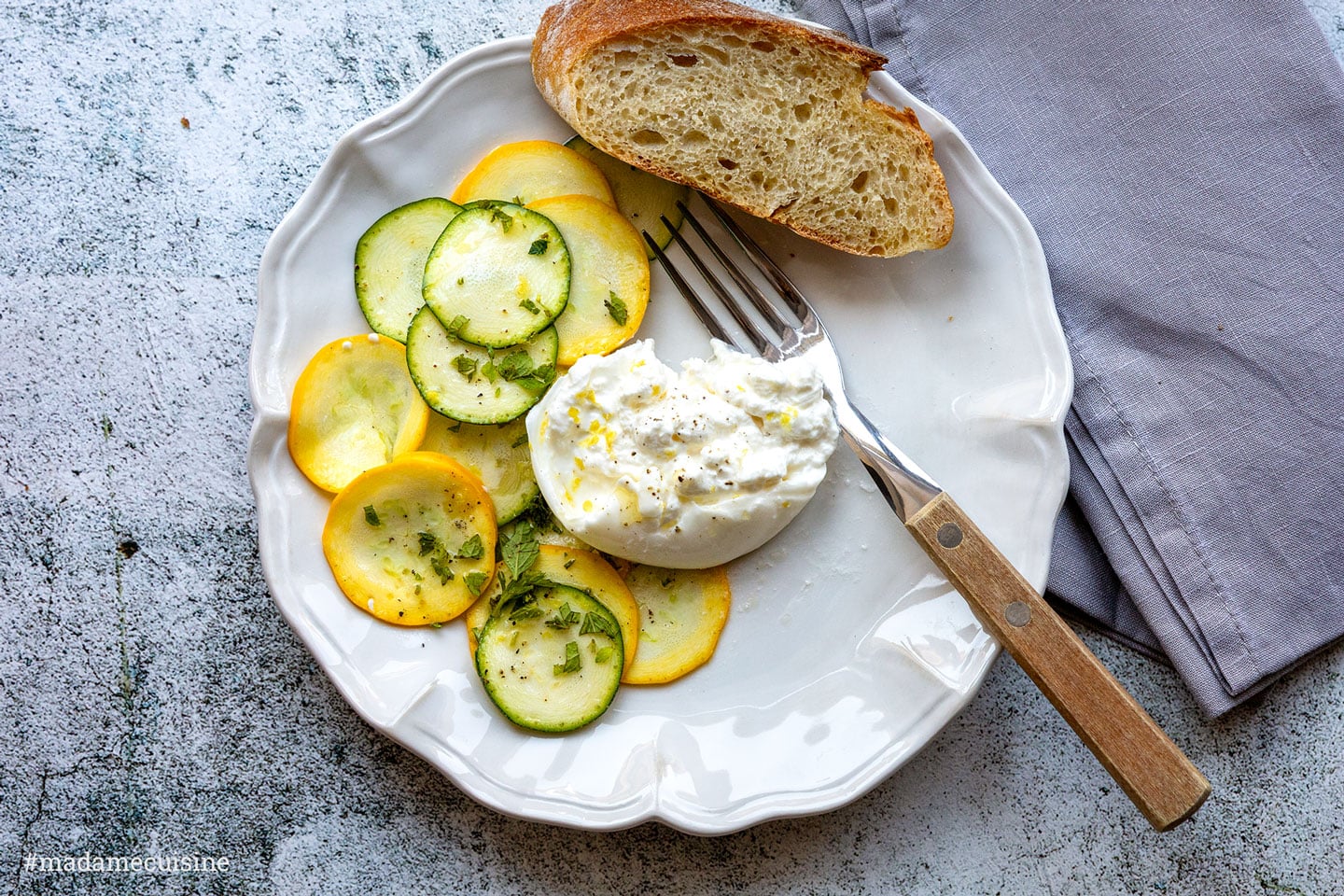 Zucchini-Carpaccio mit Burrata und Brot auf Teller