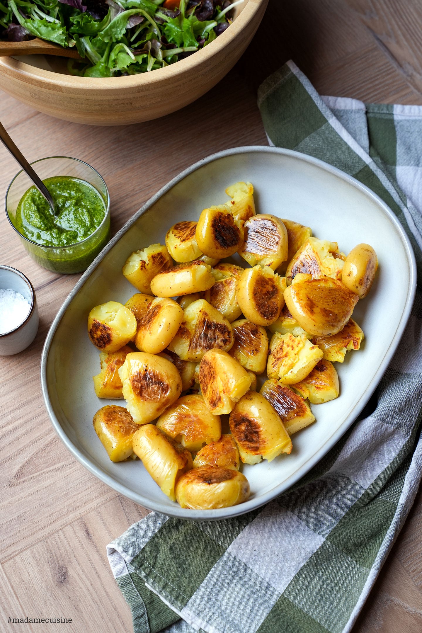 Knusprig gebratene Kartoffeln in einer ovalen Schale, im Hintergrund Salatschüssel und Pesto