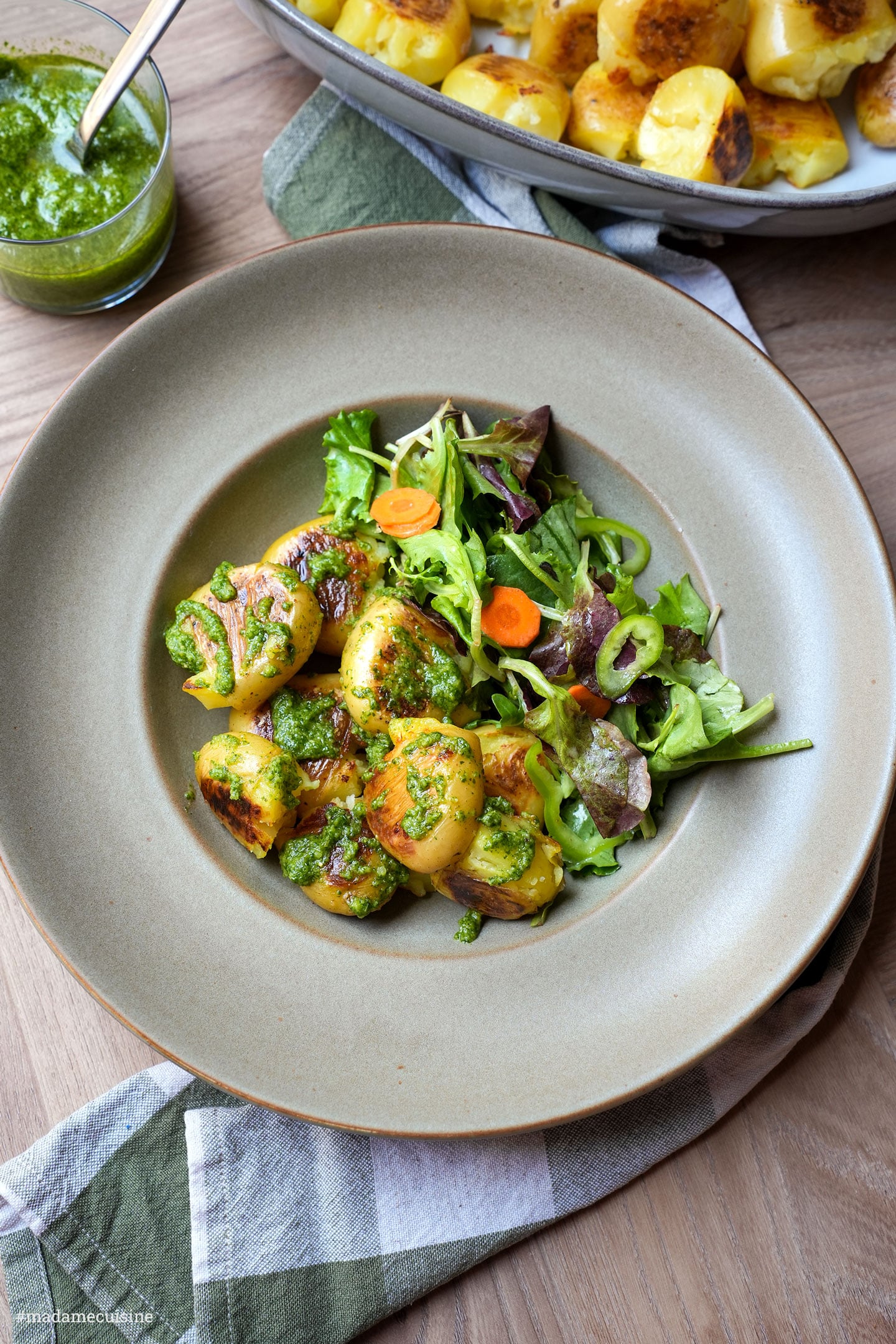 Draufsicht auf gebratene Kartoffeln mit Pesto und Salat, im Hintergrund eine Schüssel mit weiteren Kartoffeln