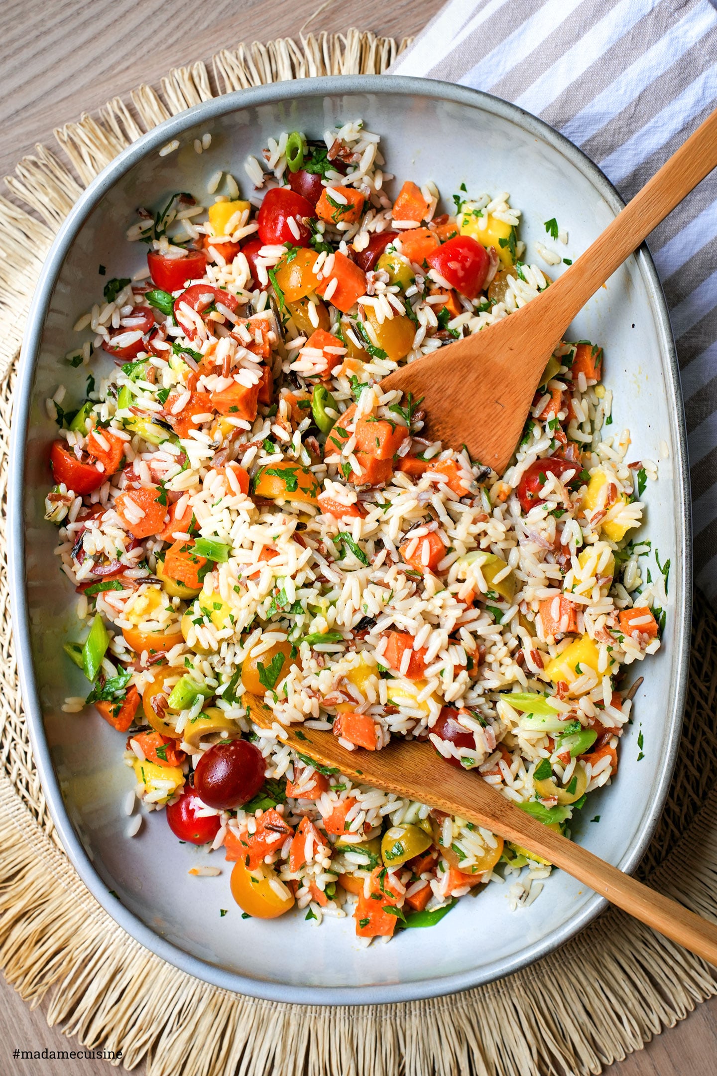 Wildreissalat mit Mango und Süßkartoffel in grauer Schüssel mit Holzlöffel