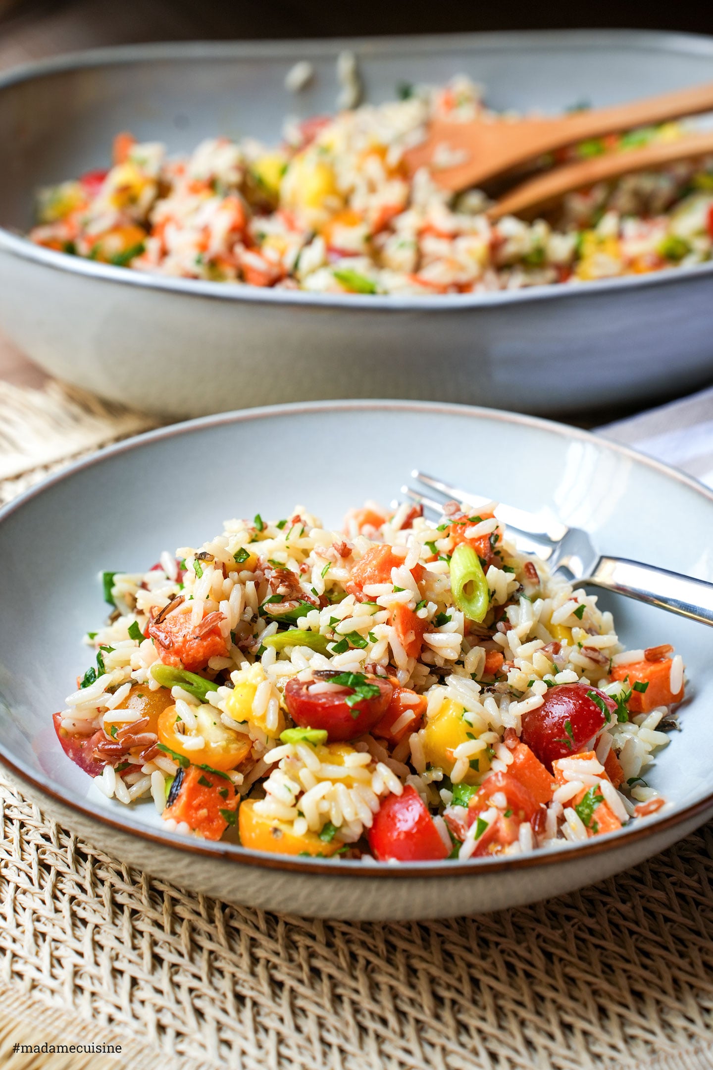 Angerichteter Wildreissalat mit Mango, Süßkartoffel und Frühlingszwiebeln auf grauem Teller