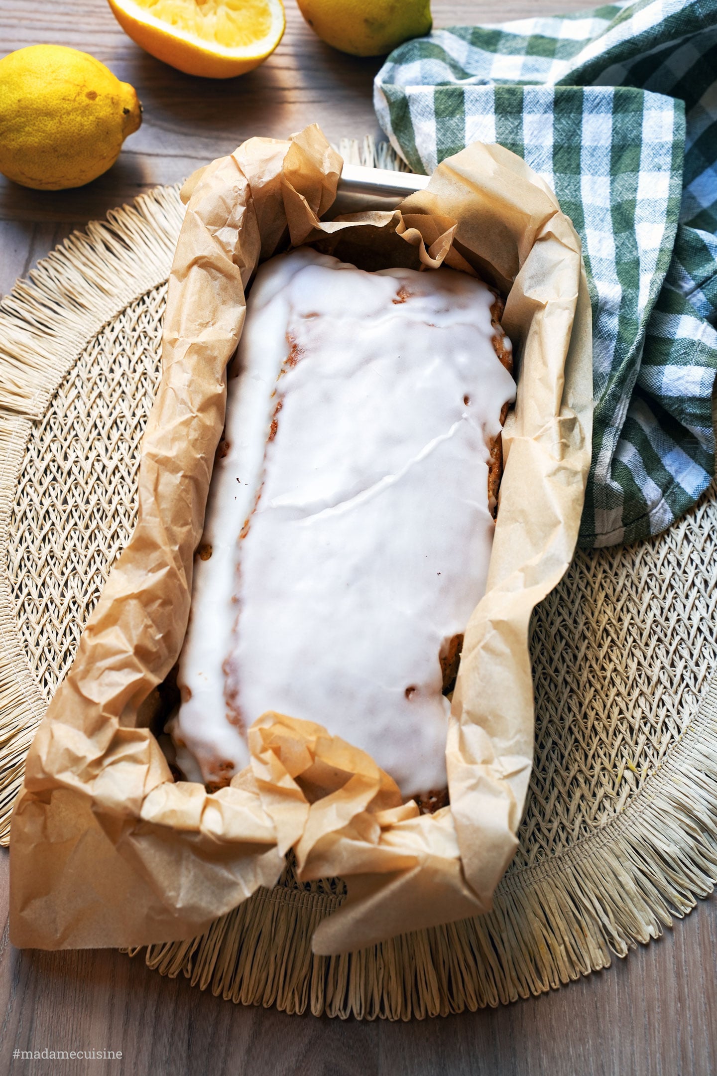 Zitronen-Mandel-Mohn-Kuchen im Backpapier, daneben die frischen Zitronen