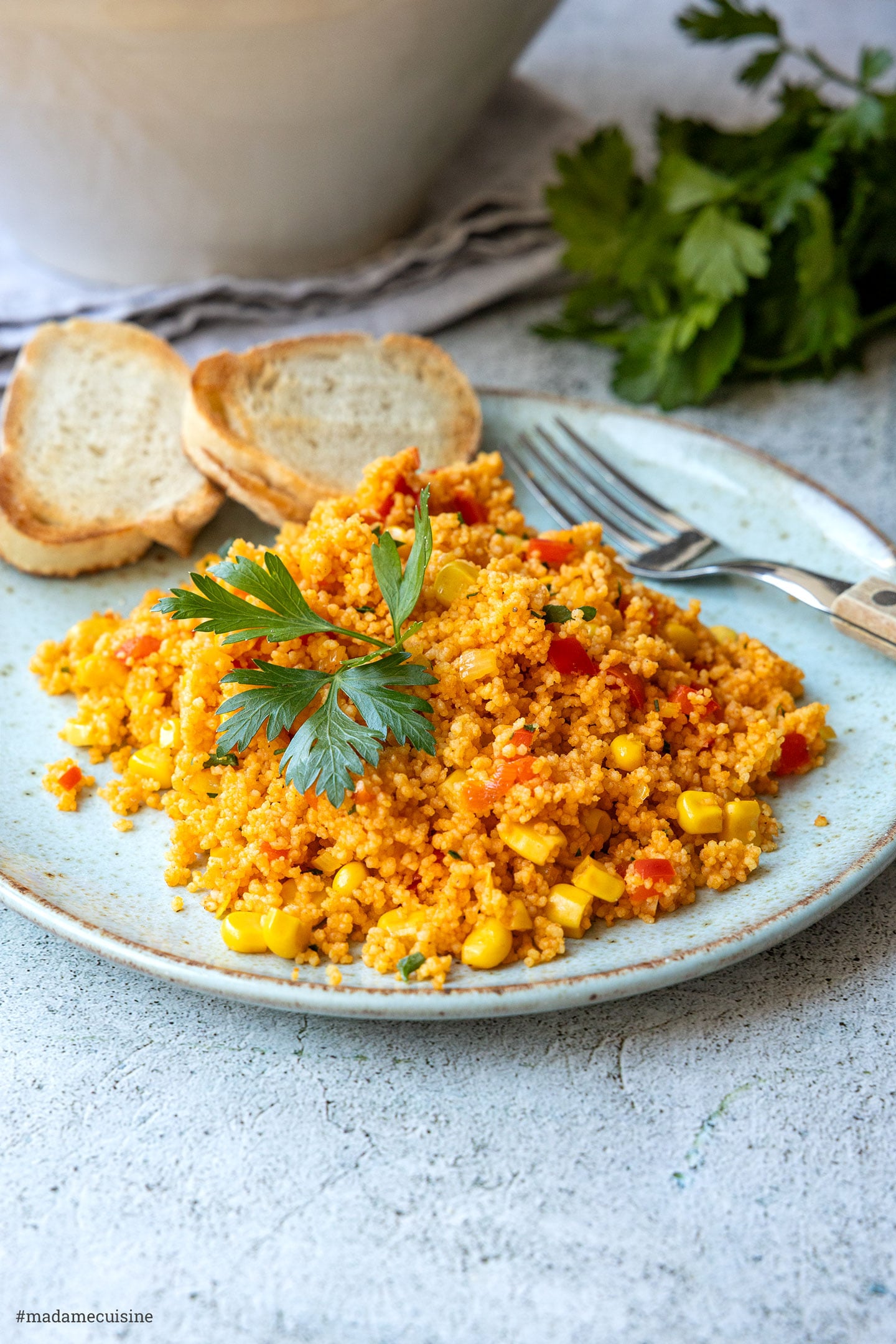 Seitliche Nahaufnahme des Couscous-Salats auf einem Teller mit geröstetem Baguette und Petersilie