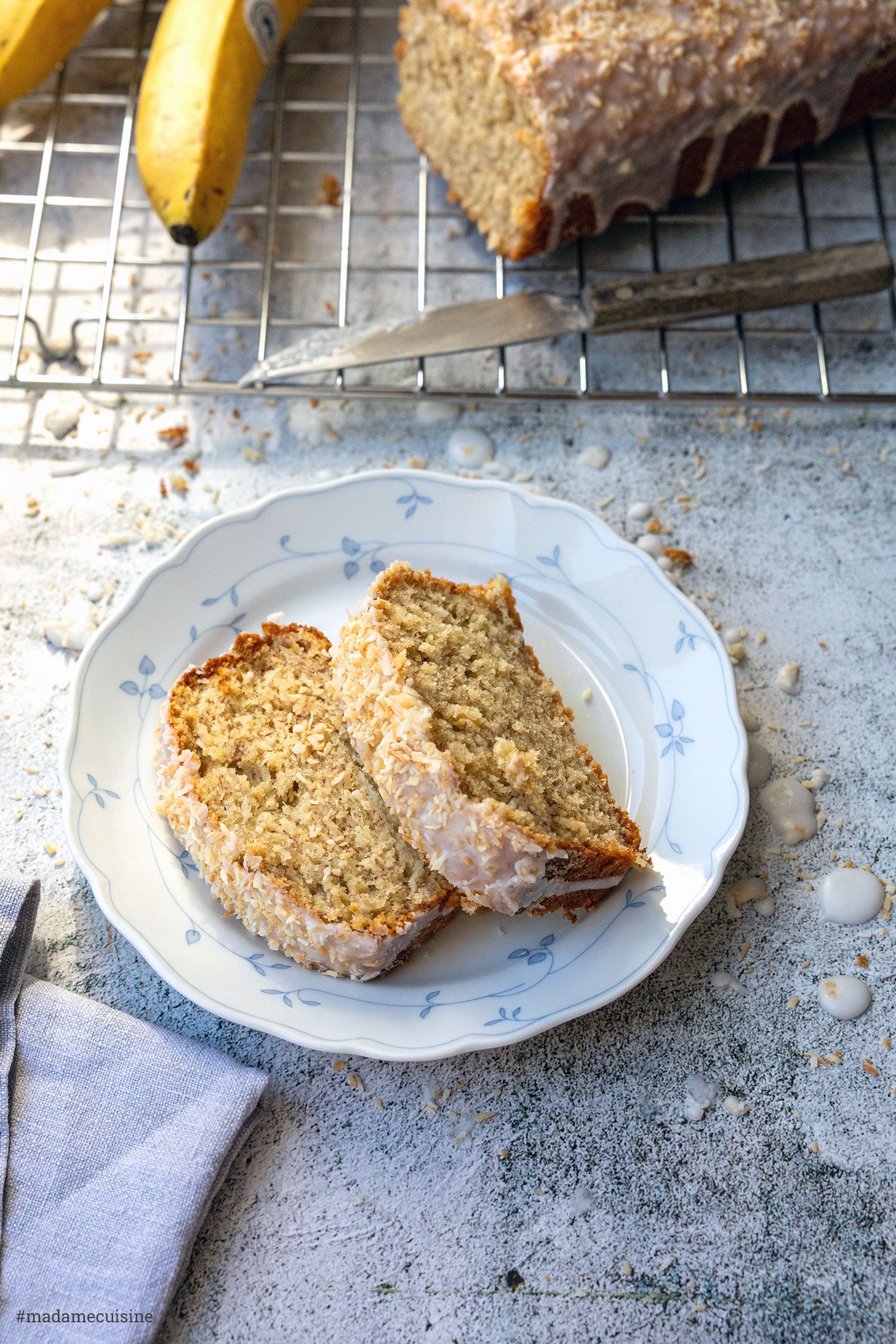Kokos-Bananenbrot in Scheiben von oben, daneben Kuchengitter und Bananen
