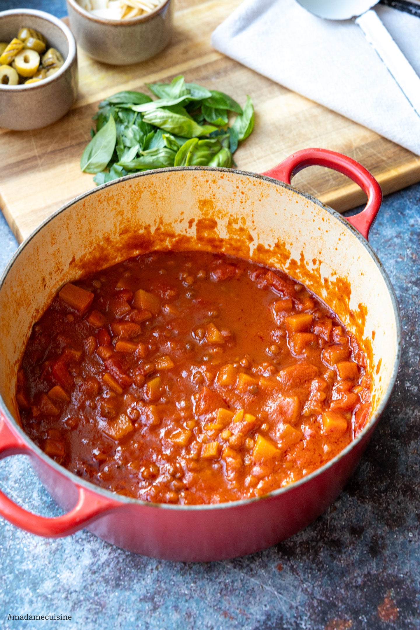 Würzige Tomatensauce mit Butternut-Kürbiswürfeln und Linsen im roten Schmortopf