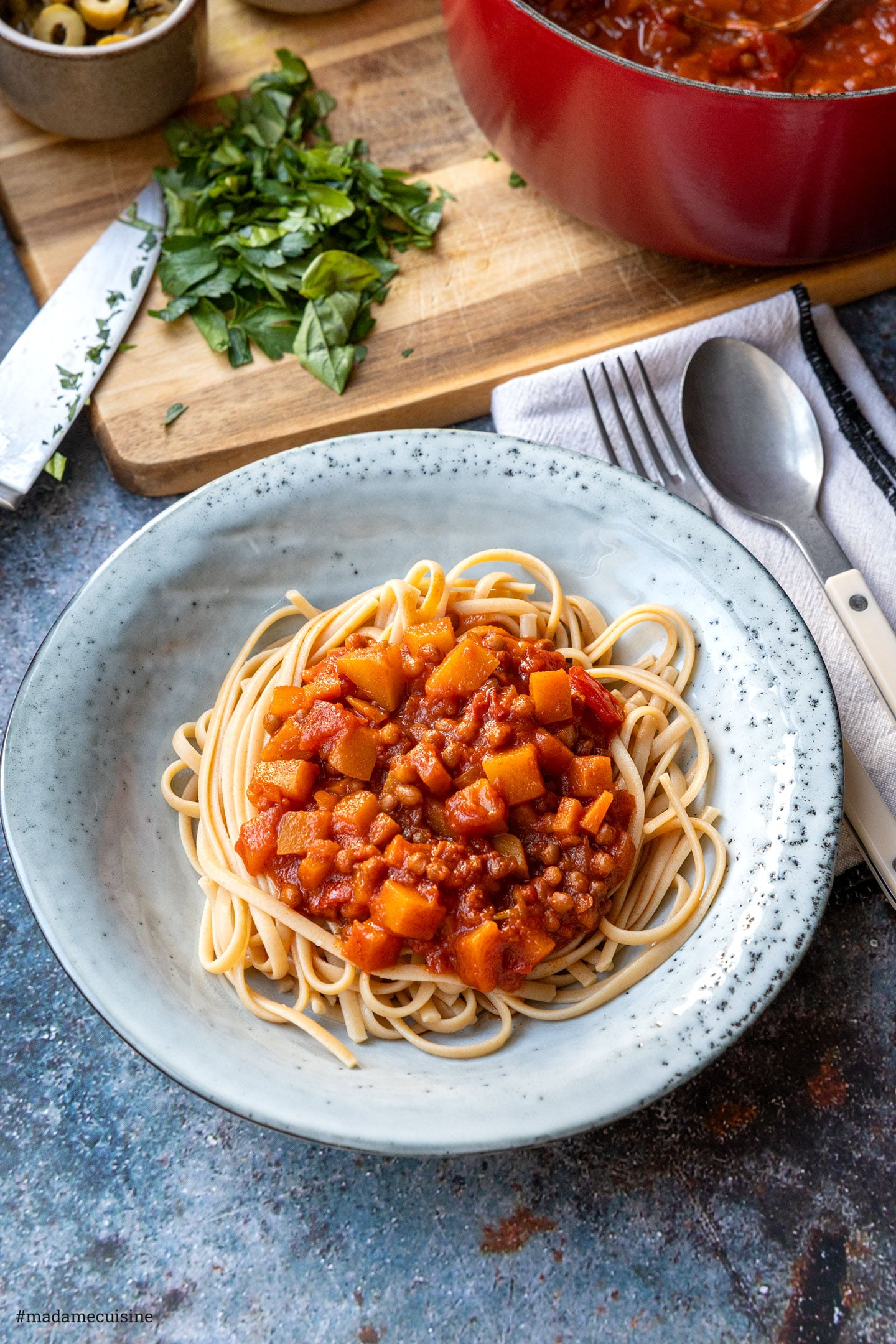 Vegetarische Bolognese mit Kürbis und Linsen auf Linguine, daneben Besteck und Leinentuch
