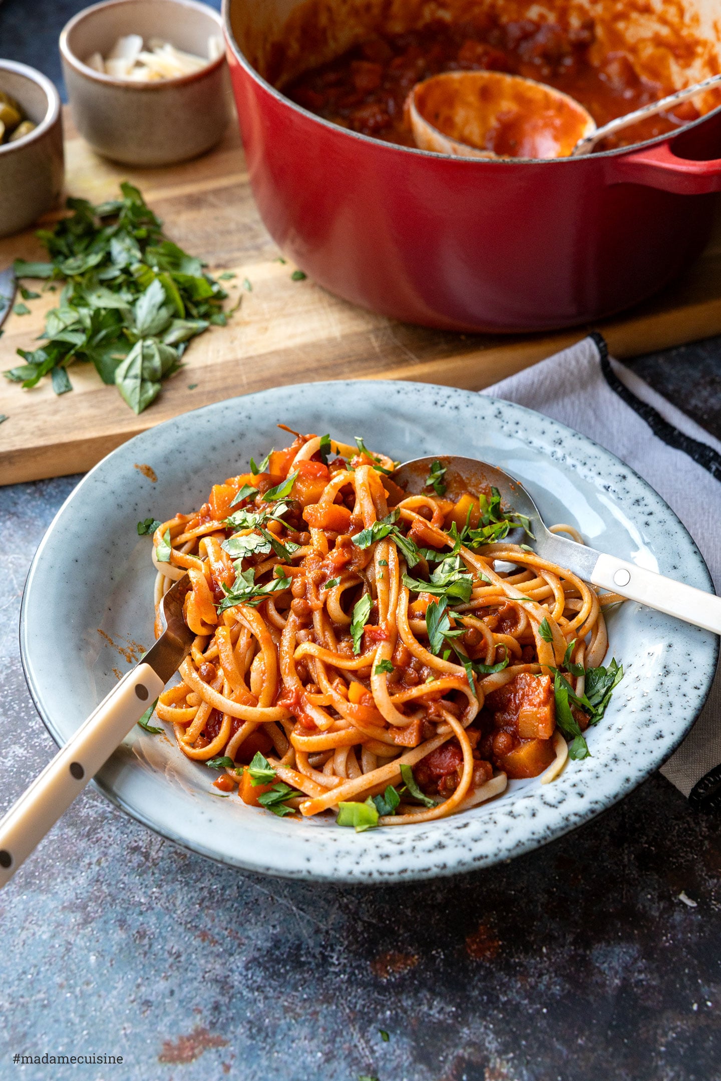 Pasta mit Kürbis-Linsen-Bolognese, mit Löffel und Gabel aufgedreht