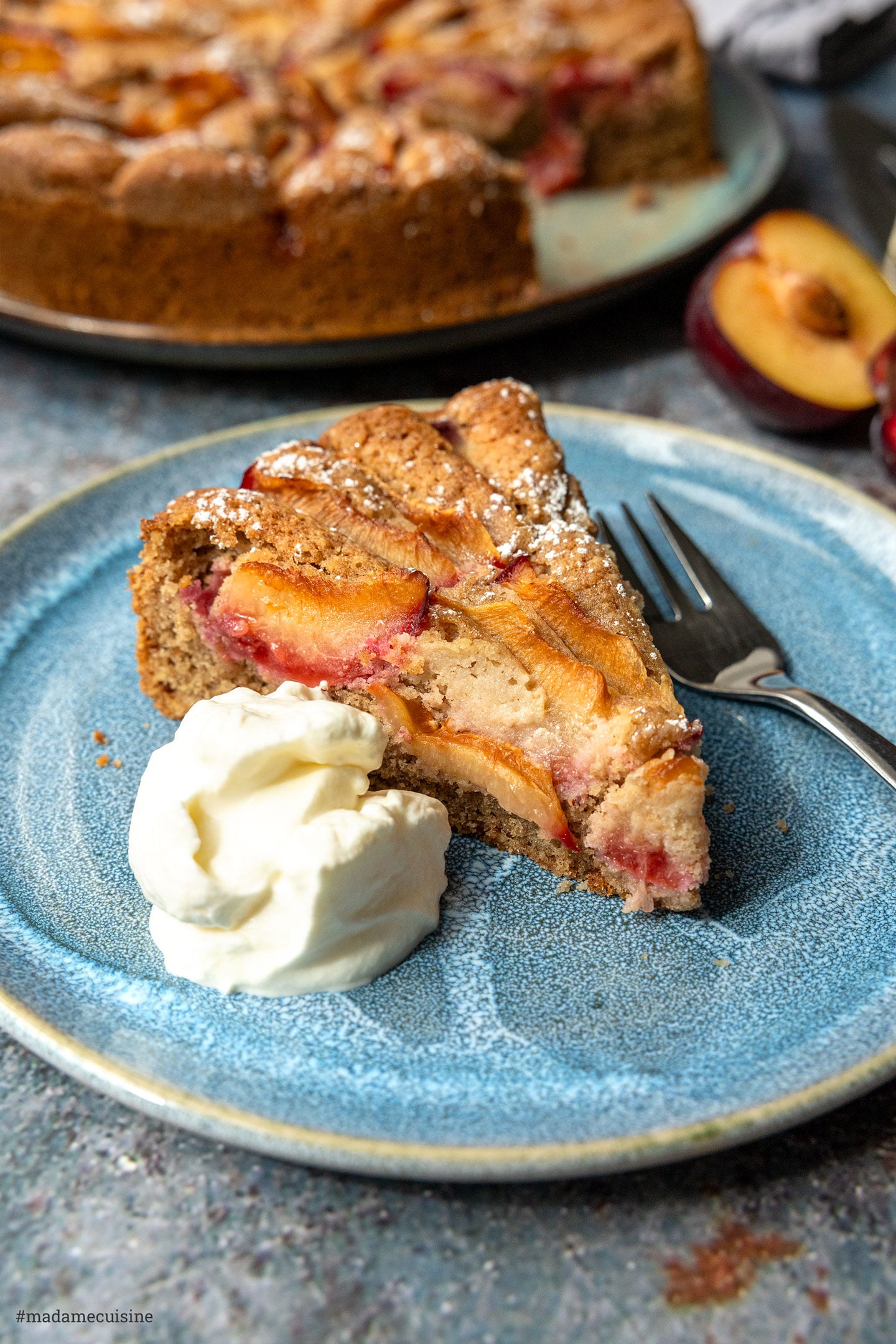 Pflaumenkuchen mit Buchweizenmehl, Kuchenstück mit einem Klecks Sahne