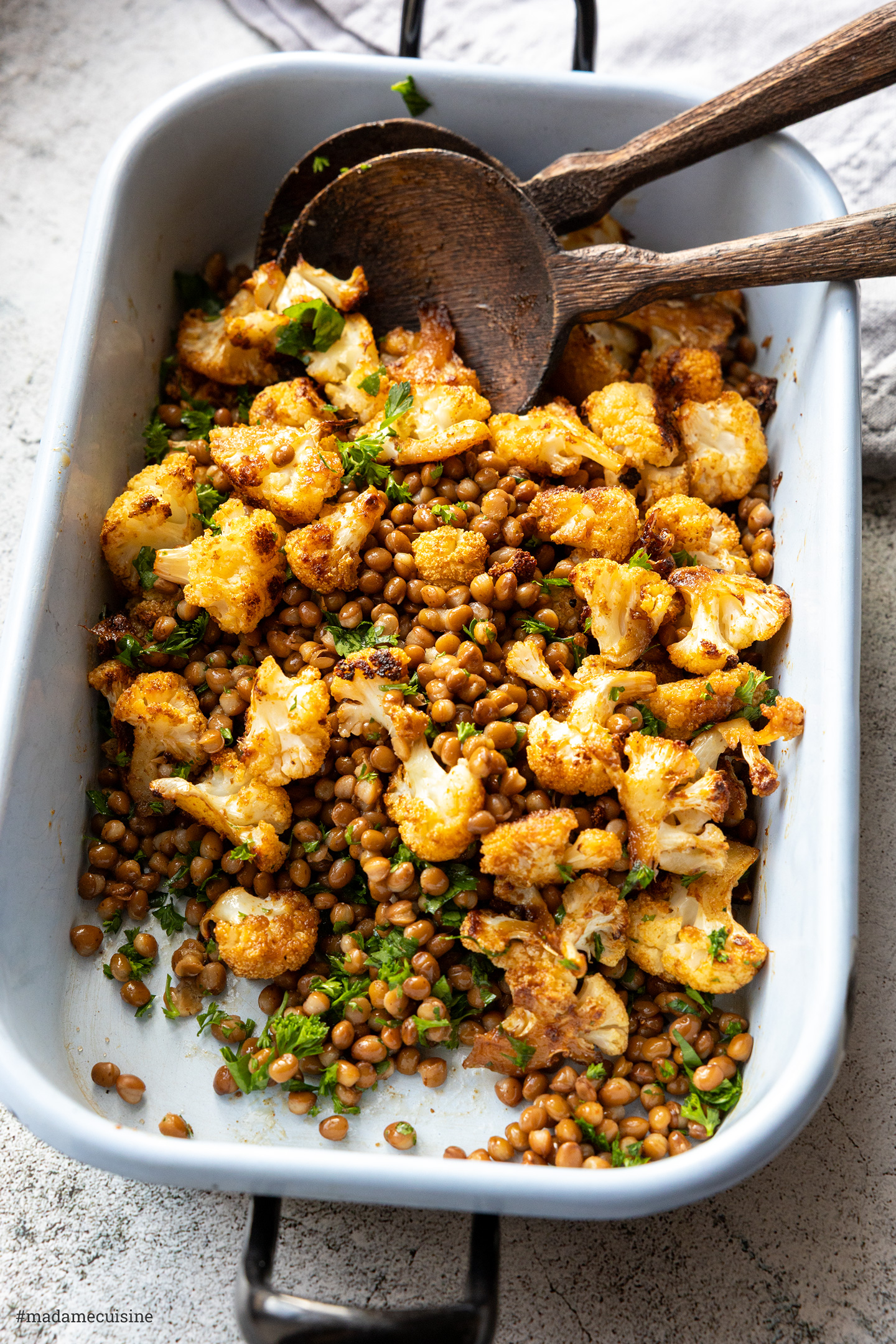Lauwarmer Salat in der Emaille-Ofenform, serviert mit zwei Holzlöffeln