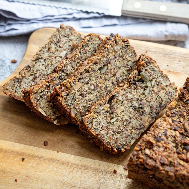 Hafer-Vollkornbrot in dicken Scheiben auf einem Holzbrett, daneben ein Brotmesser