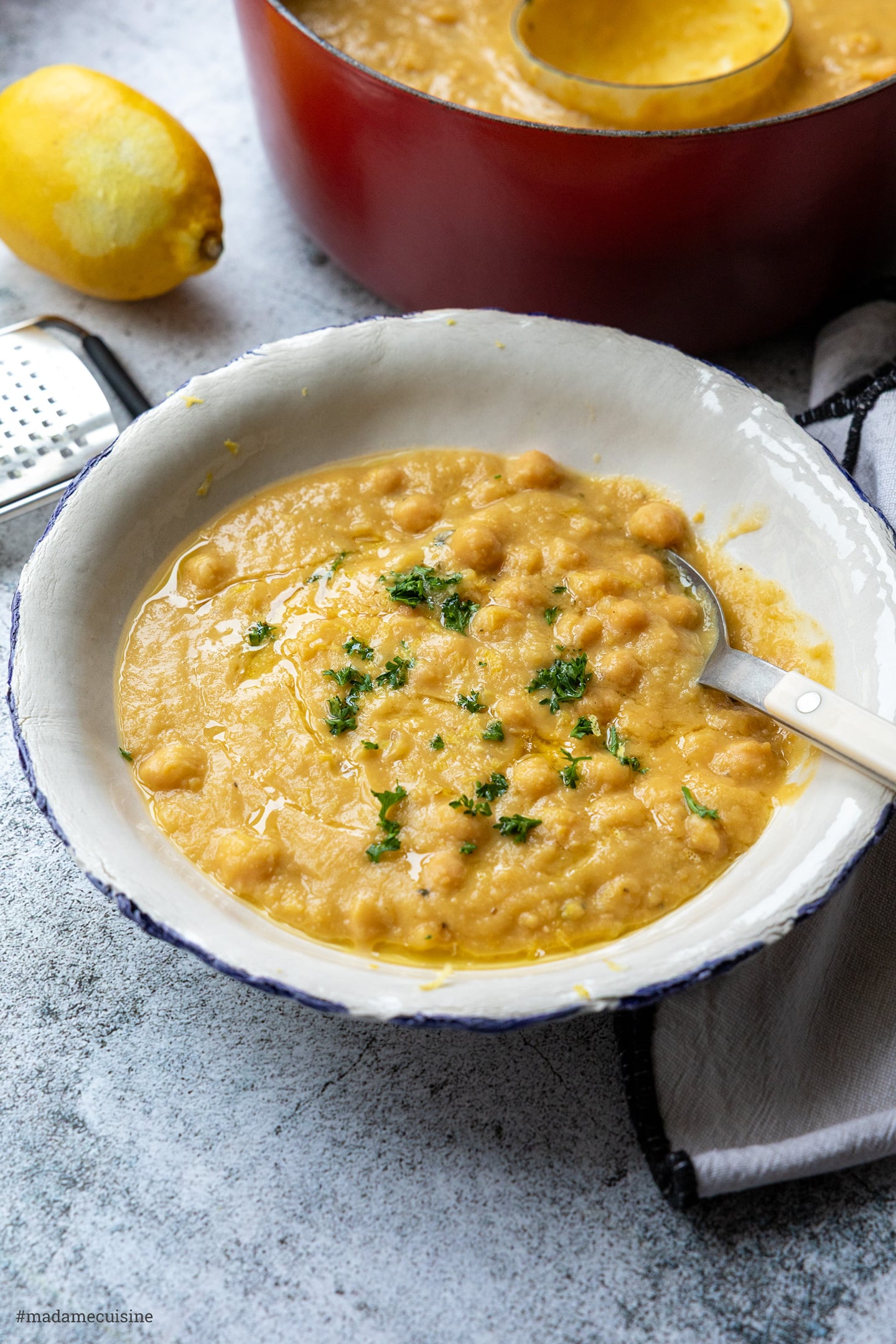 Servierfertige griechische Kichererbsensuppe mit Zitrone und Reibe im Hintergrund