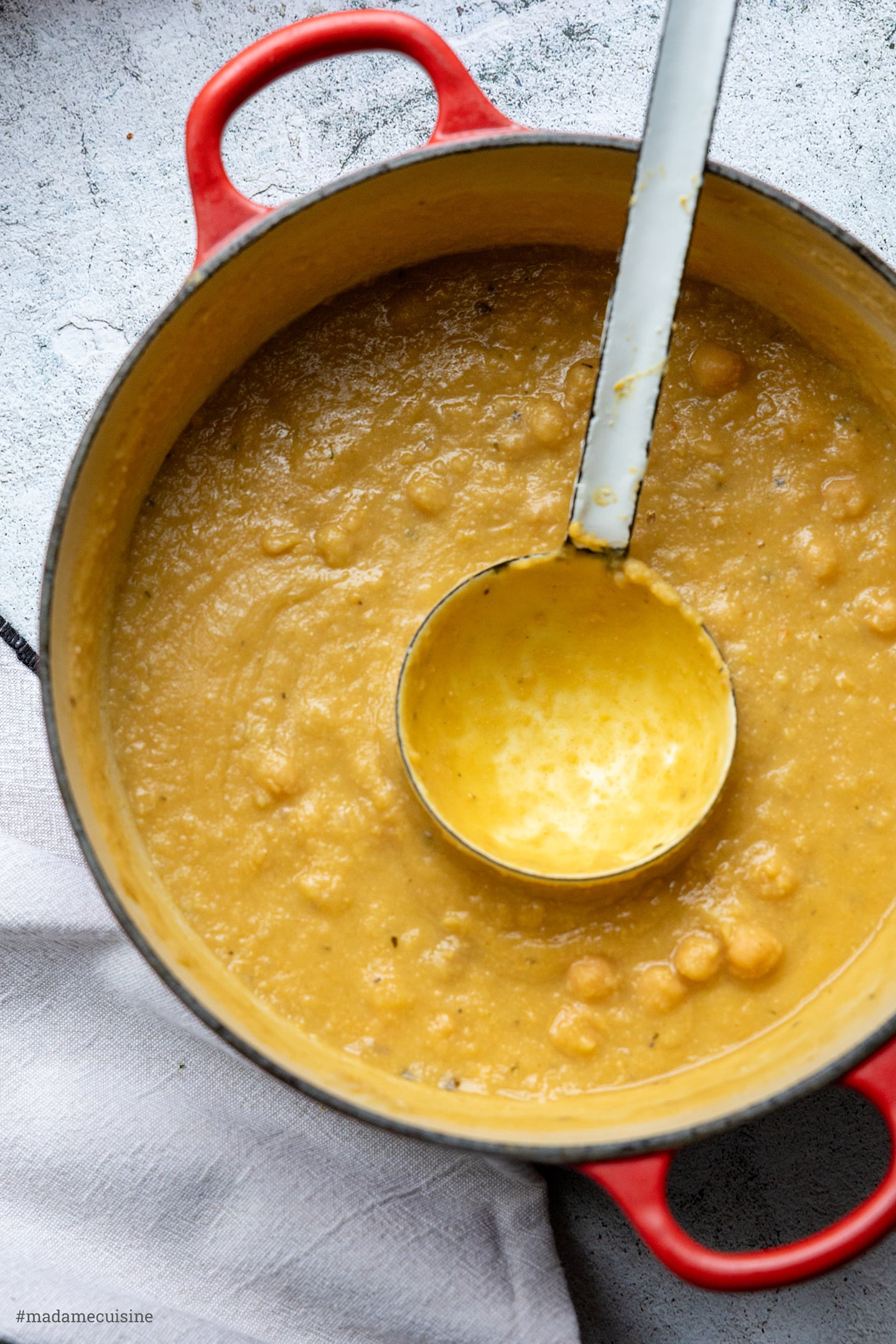 Griechische Kichererbsensuppe in der Draufsicht im roten Topf mit Schöpfkelle