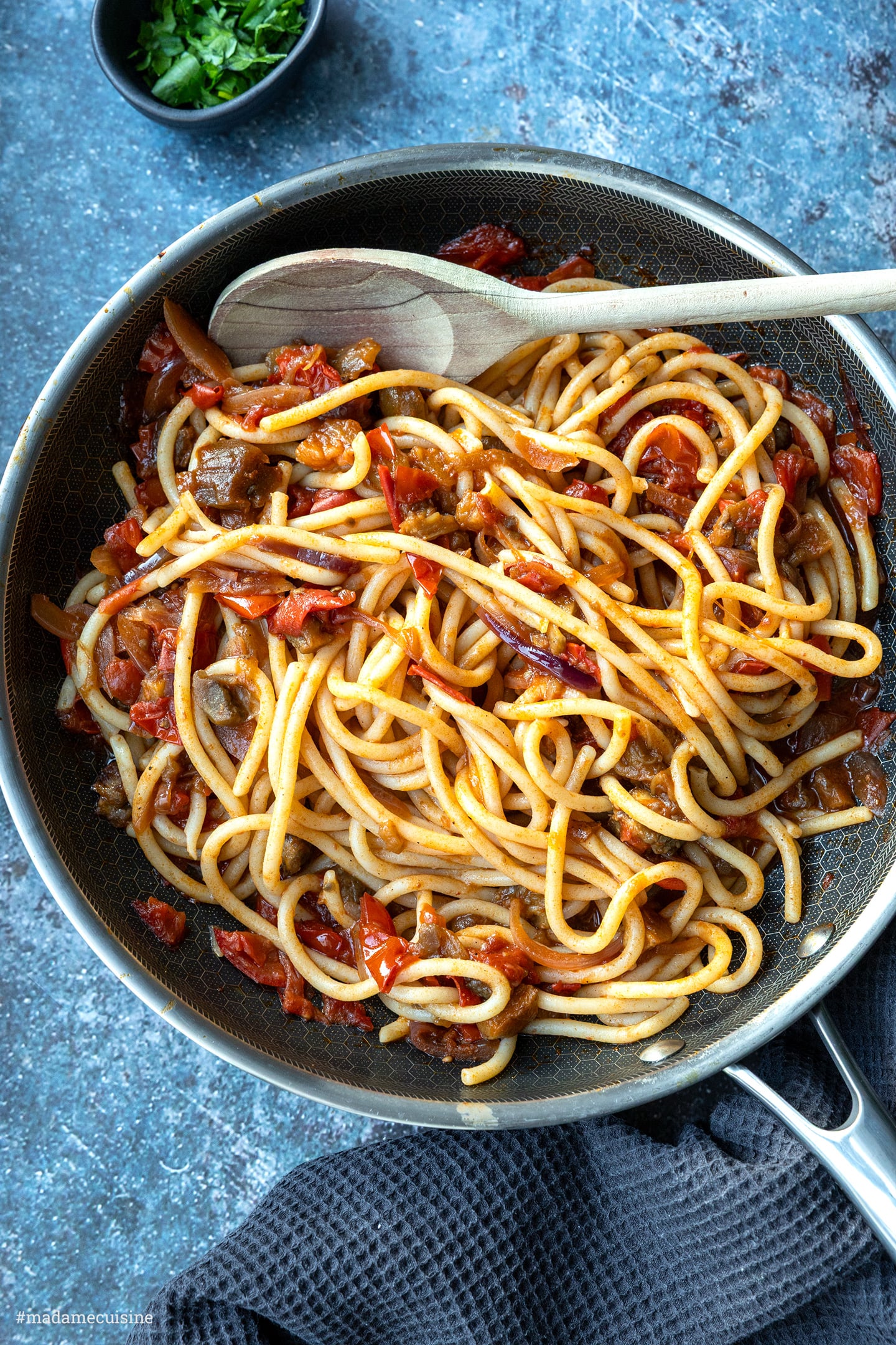Handgerollte Pasta in Tomatensauce mit Aubergine, Pfanne mit Holzlöffel