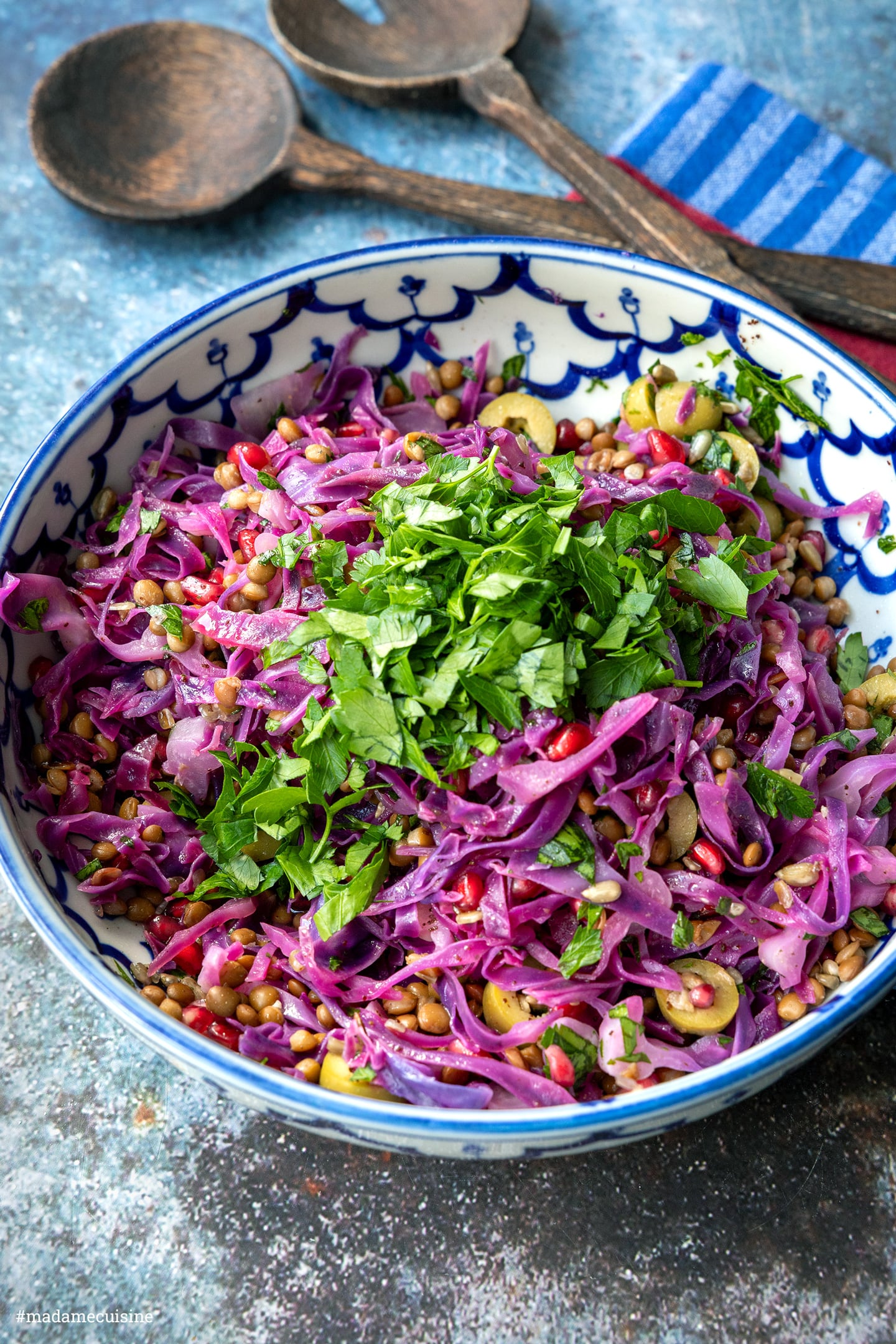 Frisch gehackte Petersilie auf Rotkohl, Linsen und Oliven in einer blau-weißen Schüssel