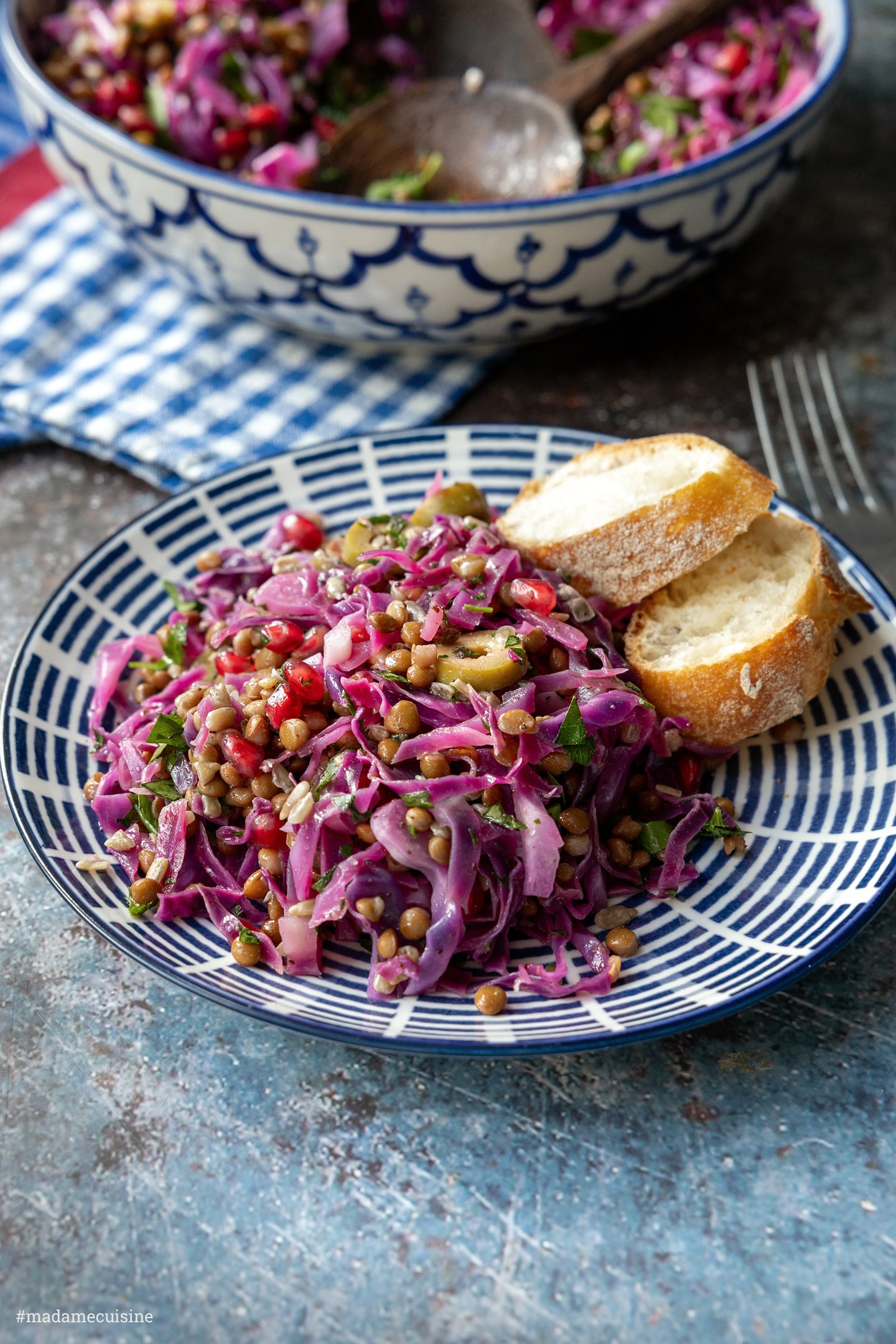Rotkohl-Linsensalat auf gestreiftem Teller, dahinter eine Schüssel mit Salat